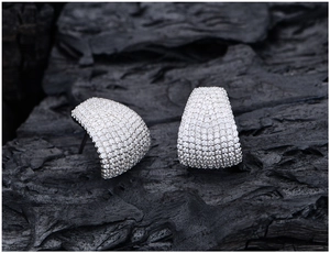 Macro detail of high-quality pavé micro-set cubic zirconia on wide curved silver earrings