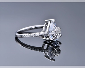 Detail of pear-cut ring with floral side stones and diamond-accented silver band