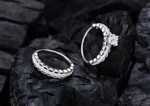 Detail of S925 silver stamp on diamond lace rings against a black stone backdrop