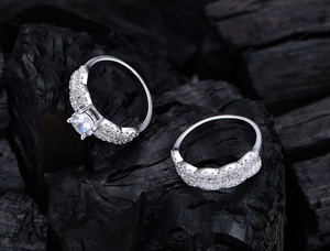 Macro shot of silver zircon rings with wave texture on dark charcoal background
