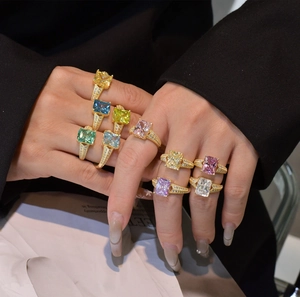 Close-up of model wearing multiple 14k gold plated rings with colorful ice cut stones
