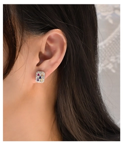 Detail view of rectangular colorful zircon stud earrings worn on a female ear