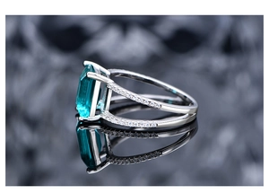 Macro view of emerald-cut dark green gemstone ring with pavé side stones on silver band