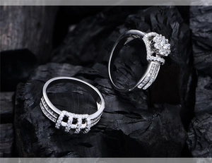 Macro detail of S925 silver halo ring and matching wedding band on charcoal texture