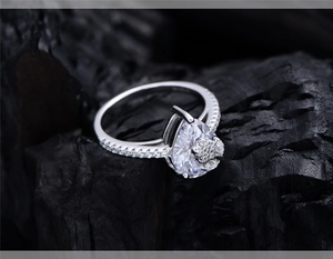 Macro shot of silver ring with pear-shaped center stone and intricate floral diamond setting