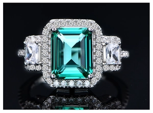 Macro shot of an emerald cut green gemstone ring with side stones on black background