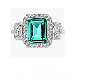 Macro shot of emerald-cut green gemstone with side baguette diamonds and silver band
