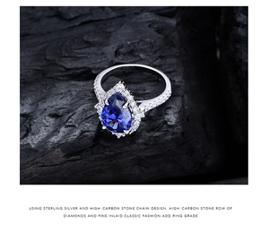 Macro shot of a 925 sterling silver pear-cut blue sapphire ring on a textured dark background