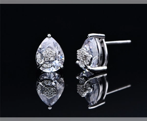 Detailed view of silver flower earrings with pear-shaped cubic zirconia on black base