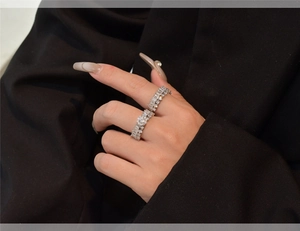 Close-up of two stacked S925 silver rings with baguette and round cut diamonds on hand