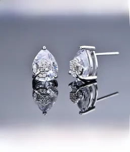 Macro shot of silver stud earrings featuring pear-shaped stones and micro-pave floral details