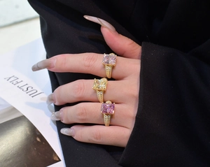 Detailed close-up of three radiant rectangle-cut gemstone rings in pink, yellow, and purple