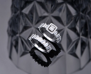 Macro detail of S925 silver rings with emerald cut cubic zirconia on black mirror surface