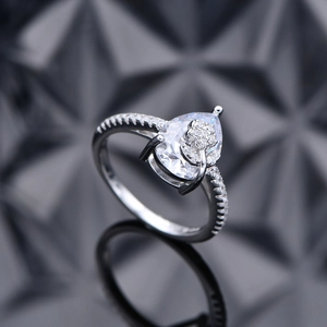 Pear cut diamond flower ring in silver with pavé setting on a black mirror background
