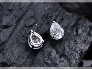 Close-up of floral pear-cut stud earrings with silver base on black texture