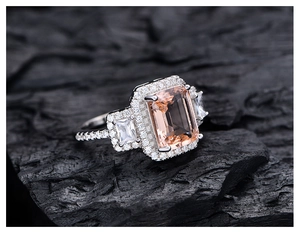 Macro shot of an emerald-cut pink morganite ring on a contrasting black textured background