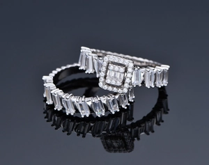 Macro shot of silver S925 geometric rings with baguette-cut zircons on a black mirror