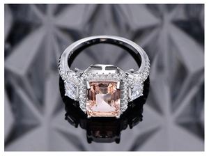 Macro detail of emerald-cut pink morganite ring with pavé halo and silver band