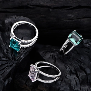 925 silver ring set with emerald cut dark green and pink synthetic diamonds on wood