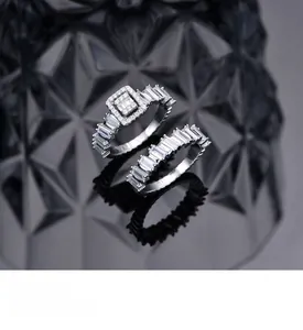 Detail of stacked S925 silver rings set with emerald-cut cubic zirconia on dark background