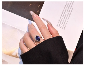 Close-up of pear-cut tanzanite ring worn by a model against a magazine backdrop