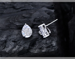 Macro shot of silver flower earrings with pear-shaped cubic zirconia on black charcoal