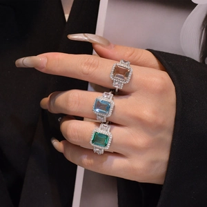 Macro shot of rectangular emerald cut rings in green, blue, and champagne colors