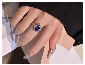 Detailed view of pear cut blue sapphire ring with halo diamonds on a hand