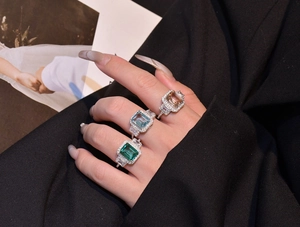 Macro shot of three emerald-cut halo rings in emerald, aquamarine, and champagne tones