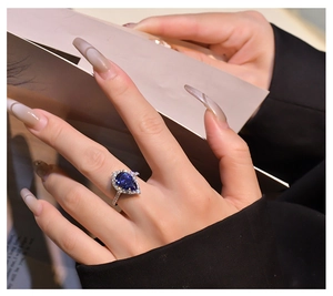 Macro detail of pear-shaped blue sapphire ring with halo diamonds on S925 silver band