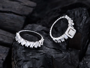 Macro shot of S925 silver rings with baguette-cut zircon on dark textured surface