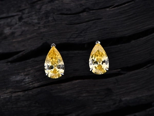 Macro shot of pear-cut yellow carbon diamond earrings with S925 sterling silver three-claw setting