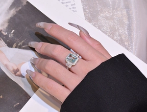 Macro detail of silver ring featuring emerald-cut light blue gemstone with halo diamonds