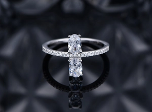 Macro shot of oval cut diamond ring with side pavé stones and symmetrical reflection