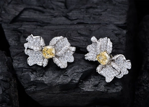 Macro di orecchini a fiore in argento con gemma gialla su sfondo di carboncino