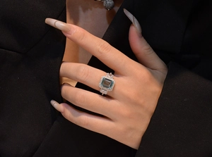 Macro shot of an emerald-cut blue gemstone ring surrounded by small white zirconias