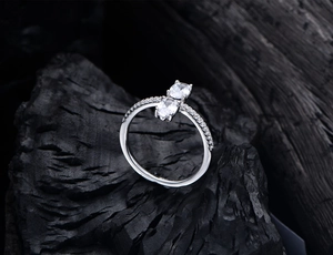 Macro shot of 925 silver ring featuring two oval cut diamonds on a dark textured rock
