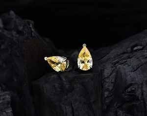 Macro view of pear-cut yellow gemstone earrings with silver three-prong setting