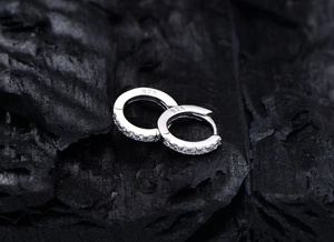 Macro shot of 925 sterling silver earrings with inlaid cubic zirconia on charcoal background