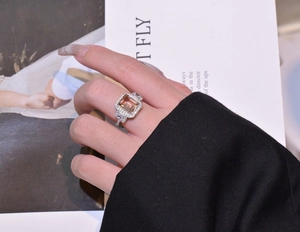 Detailed close-up of a luxury emerald-cut champagne gemstone ring worn by a model