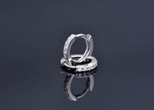 Macro detail of silver huggie earrings with white cubic zirconia and snap closure