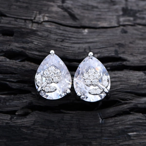 Elegant floral pear-cut drop earrings with sparkling crystals on black wood background