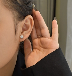 Close-up of classic 5mm round sparkling diamond stud earrings on a female model