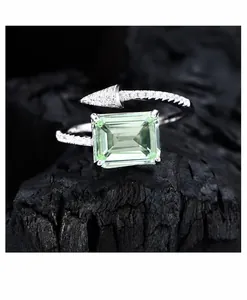 Dettaglio macro dell'anello con pietra verde smeraldo e freccia di diamanti su roccia nera
