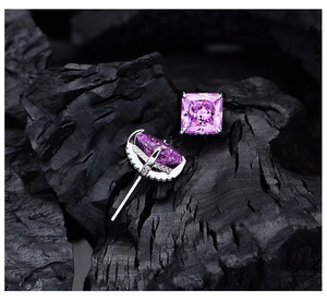 Detail of princess cut pink diamond stud earrings with side pave setting on charcoal