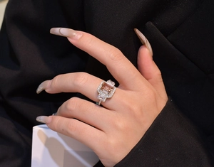 Detailed close-up of emerald-cut champagne gemstone ring on silver band with side stones