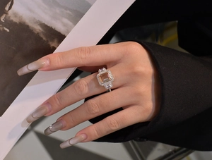 Detailed macro shot of rectangular emerald cut champagne ring worn by a model