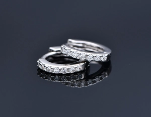 Macro shot of silver huggie earrings with a row of sparkling white cubic zirconia stones