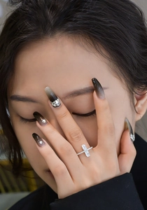 Close-up of a silver cross ring with two oval main stones and pavé set white zircons