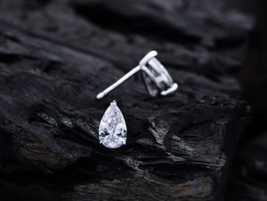 Macro detail of pear-cut sparkling zircon stud earrings with classic 3-prong silver setting